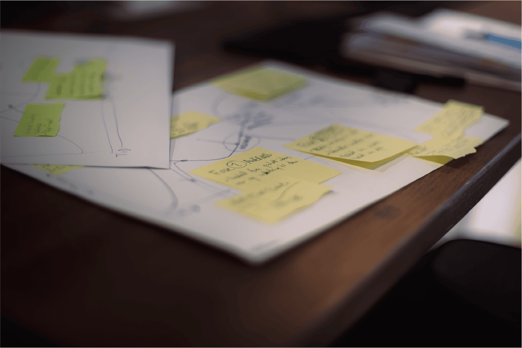 nærbilde av post-it lapper og ark med notater på et bord